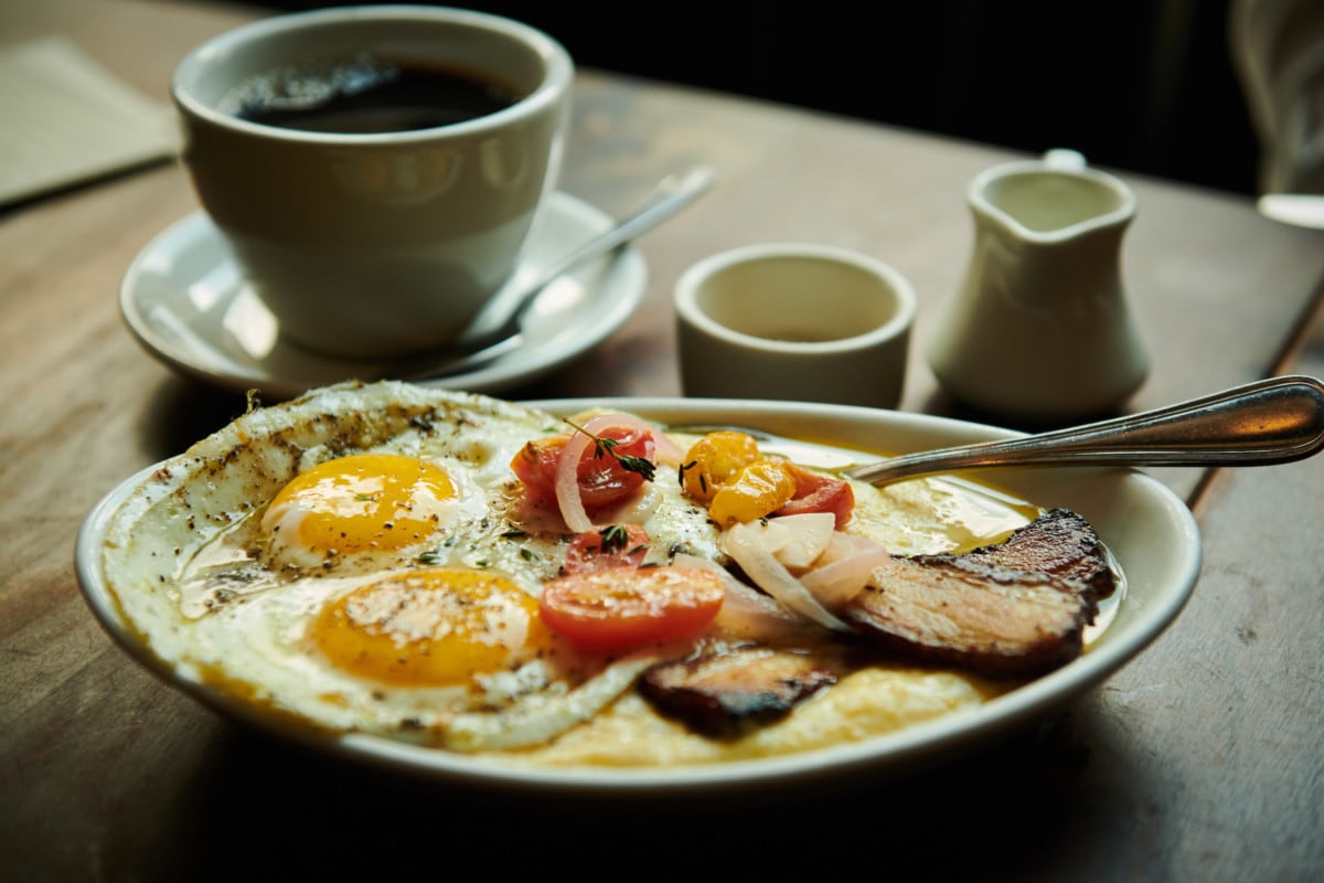 Plate of fried eggs and bacon with cup of coffee