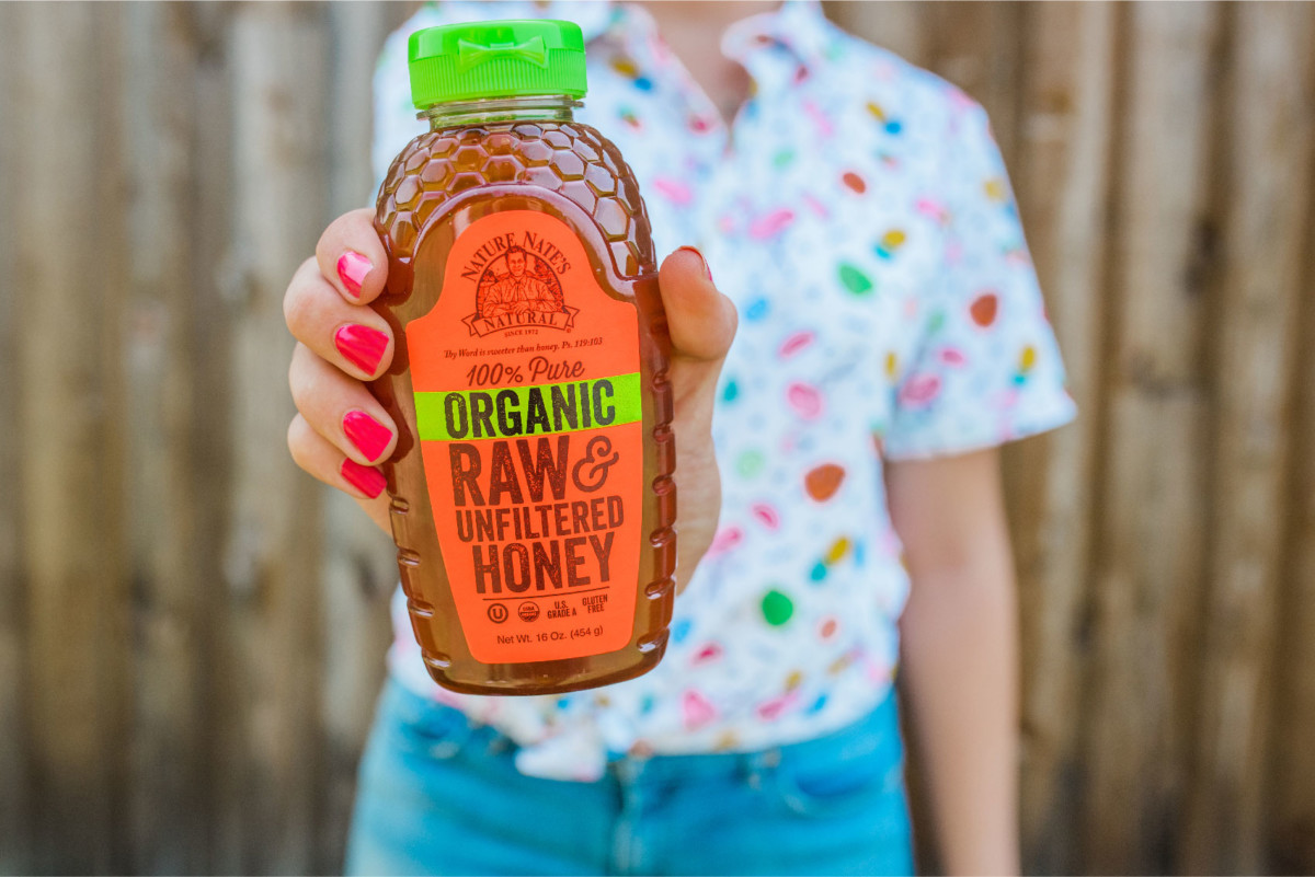 Girl holding Organic Raw & Unfiltered Honey bottle